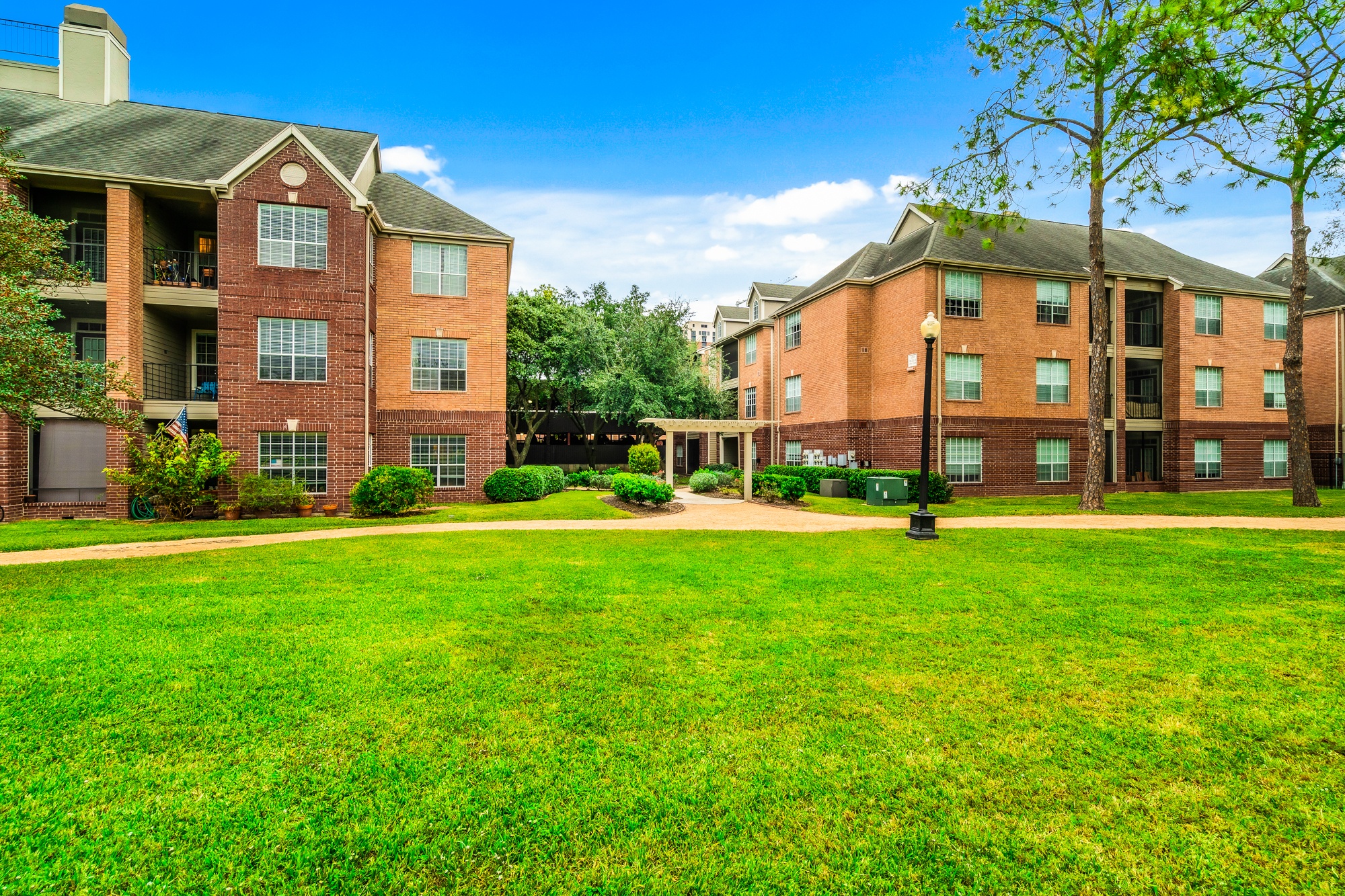 A large grassy area in front of two red brick apartment buildings.